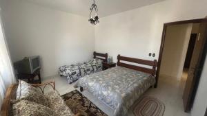 a room with two beds and a couch and a tv at Pousada Casa da Vó Dita in Ouro Fino