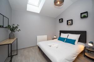 a bedroom with a large white bed with blue pillows at Gîte Chelona d'Hermann - parking - Chelona'Loc in Braud-et-Saint-Louis