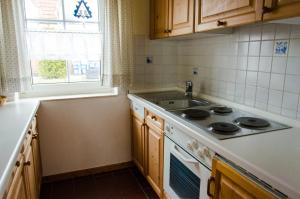 Una cocina con estufa, fregadero y ventana. en Ferienhaus Seewiefken, en Hooksiel