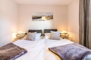 two beds in a bedroom with two lamps at Ferienwohnung Ebbe in Hooksiel