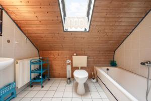 a bathroom with a toilet and a tub and a window at Ferienhaus Fülling in Hooksiel