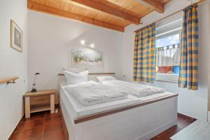 a white bed in a room with a window at Ferienhaus Fülling in Hooksiel