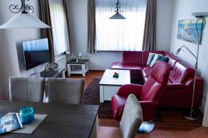 a living room with a red couch and a table at Ferienwohnung Krabbe in Hooksiel
