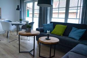 a living room with a blue couch and two tables at Ferienwohnung Wassmann Hooksiel in Hooksiel
