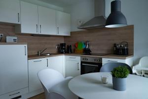 a kitchen with white cabinets and a table with chairs at Ferienwohnung Wassmann Hooksiel in Hooksiel