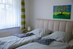 an unmade bed in a bedroom with a painting on the wall at Ferienwohnung Boje 10 in Schillig