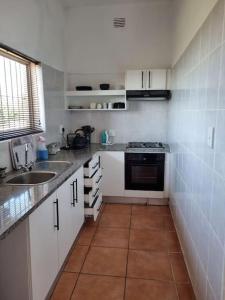 a small white kitchen with a sink and a stove at Home away sea view in Margate +9 photos