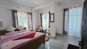 a bedroom with a bed and a table and windows at Goo Sheela Homestay in Darjeeling