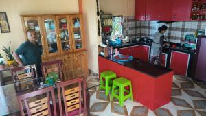 a kitchen with red cabinets and green stools at Goo Sheela Homestay in Darjeeling +17 photos