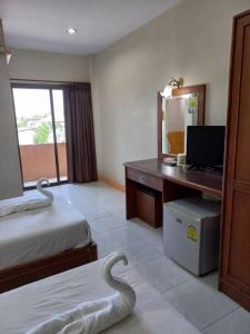 a hotel room with two beds and a desk with a mirror at ปะการังแมนชั่น in Udon Thani