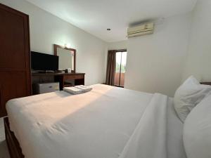a bedroom with a large white bed with a window at ปะการังแมนชั่น in Udon Thani
