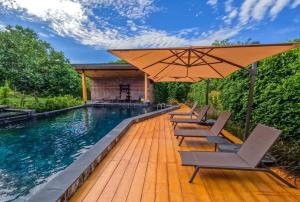 a swimming pool with chairs and an umbrella at La Levée Resort in Sai Yok