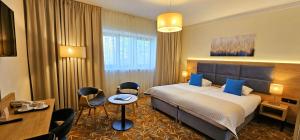 华沙巴尔纳必透中枢酒店的一间带床、桌椅的酒店房间