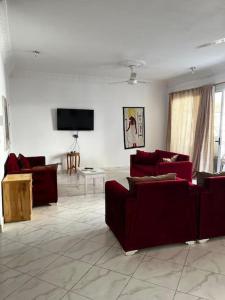a living room with red couches and a flat screen tv at Sekhmet Appartement 2 chambres in Luxor +16 photos