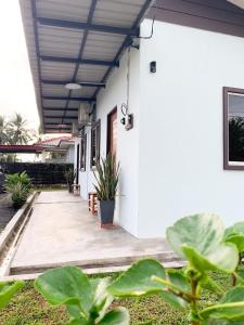 a porch of a white house with plants at Palas Tiny Homestay in Changlun