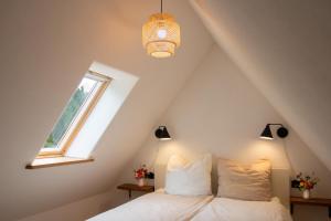 a bedroom with a bed and a window and a chandelier at Idyllisches Landhaus, Garten & Kamin, für Paare in Häven