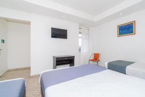 a hotel room with two beds and a television at HOTEL OASIS in Rionegro