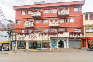 a tall red building on a street with a store at HOTEL OASIS in Rionegro