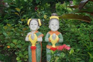 two statues of two women standing next to a bush at Bounty Resort in Haad Son