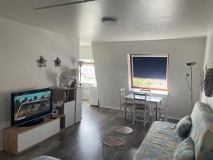 a living room with a couch and a tv and a table at Grand studio Centre-ville avec ascenseur in Calais +3 photos