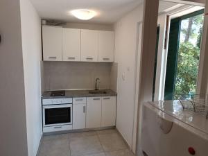 a kitchen with white cabinets and a sink and a window at House Vlasta in Primošten