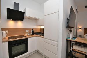 a kitchen with white cabinets and a tv on the wall at Apartment Leprin in Labin