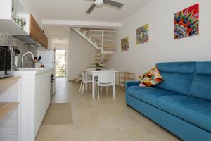 a living room with a blue couch and a kitchen at Astro apartments with direct access on the sea of Noto heritage of Unesco in Noto +33 photos