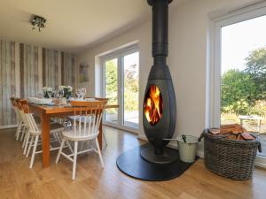 Una chimenea en una sala de estar con una mesa de comedor y un comedor. en Penhaven, en Bude