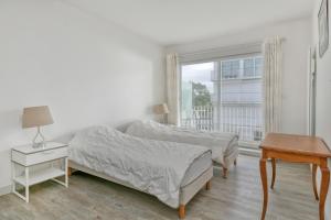 a bedroom with two beds and a table and a window at Pieds dans l'eau - Balcon vue mer in La Baule