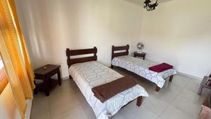 a room with two beds and a table at Pousada Casa da Vó Dita in Ouro Fino