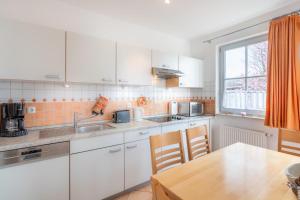 a kitchen with white cabinets and a wooden table at Helle Fewo in toller Lage mit Badewanne und Balkon in Kühlungsborn