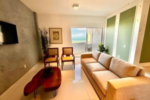 Una sala de estar con un sofá, una mesa y sillas. en Apartamentos e Suítes na Praia, en Fortaleza