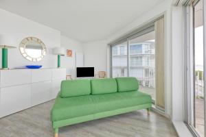 a green couch in a living room with a window at Pieds dans l'eau - Balcon vue mer in La Baule