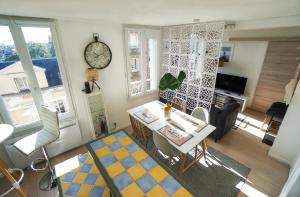 un soggiorno con tavolo, sedie e orologio di 2 pièces "Les Nuits Douces" - Calme et Lumineux - Gare à 10 min - Tram à 3 min a Le Havre