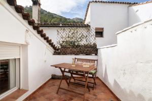 a small balcony with a wooden table on a white wall at Casa calle del Carmen in Grazalema