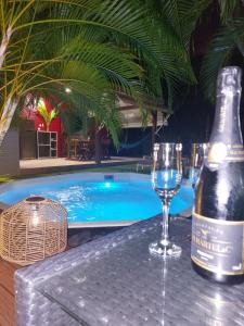 a bottle of wine and a glass next to a swimming pool at Love Lodge Guadeloupe - Love Room Romantique Saint Francois in Saint-François