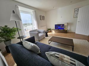 a living room with a blue couch and a tv at River Breeze 3-Bed BALCONY Apartment in Littlehampton