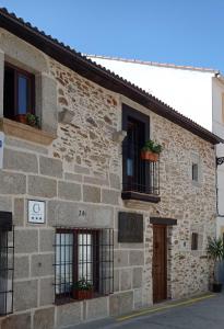 un bâtiment en pierre avec des plantes aux fenêtres dans l'établissement Ceclavinn Casa Rural, à Ceclavín