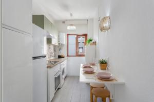 a kitchen with white cabinets and a table with stools at Martimar Candelaria in Candelaria