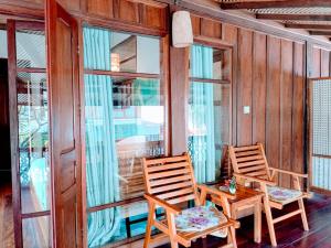 two chairs and a table on a porch with windows at Ireenkevin guesthouse in Luang Prabang