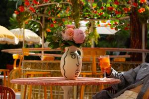 a vase with flowers sitting on a table with a glass at Hôtel Juana in Juan-les-Pins