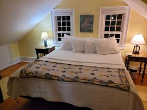 ein großes Bett in einem Schlafzimmer mit zwei Fenstern in der Unterkunft Joy Cottage in Prospect Harbor