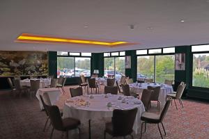 a room with white tables and chairs and windows at Shillingford Bridge Hotel in Wallingford