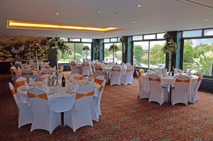 a banquet hall with white tables and chairs and windows at Shillingford Bridge Hotel in Wallingford