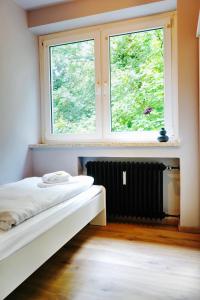 a room with a bed and two windows and a radiator at Naturnahes Apartment- 3 Betten-Waschmaschine-Parkplatz-Balkon in Wolfsburg