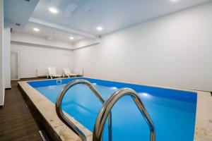 an indoor swimming pool with two metal hand rails at Emerald Borjomi Hotel in Borjomi +33 photos