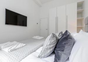 a white room with a bed with pillows and a television at Babylon Piccadilly in London