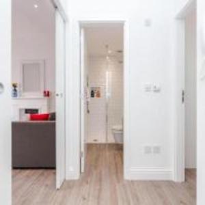 a room with white walls and wooden floors and a bathroom at Babylon Piccadilly in London
