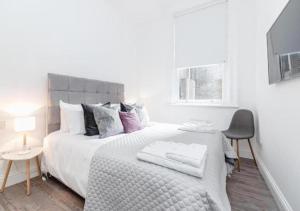 a white bedroom with a large bed and a chair at Babylon Piccadilly in London