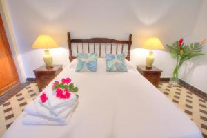 a bedroom with a bed with two lamps and flowers on it at Domaine Les hauts de Sofaia - Évasion Créole - Vue Spectaculaire in Sofaïa
